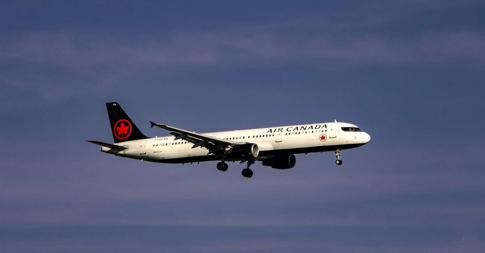 Air Canada airplane approaching for landing against a clear blue sky