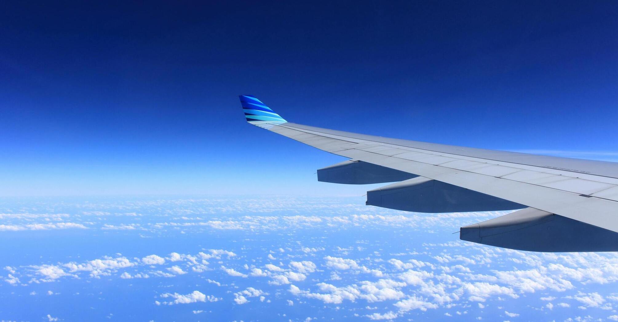 Airplane wing view above clouds and landscape