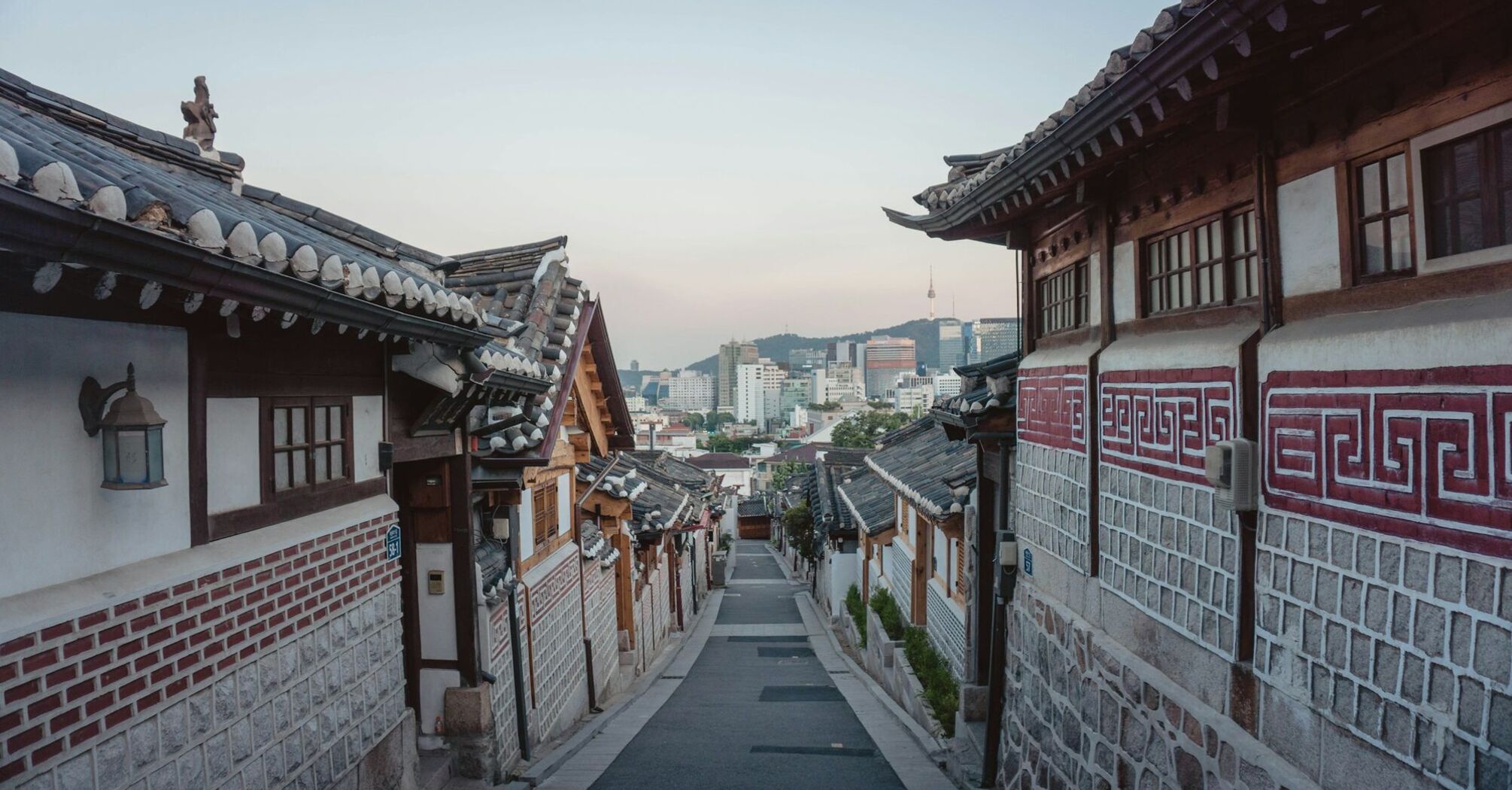 Traditional Korean hanok village with modern Seoul skyline in the background