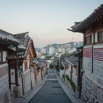 Traditional Korean hanok village with modern Seoul skyline in the background