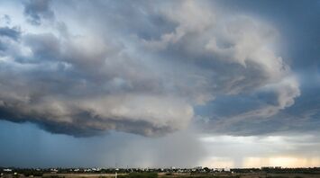 Dark storm clouds hover over a distant cityscape, signaling an impending heavy rainstorm