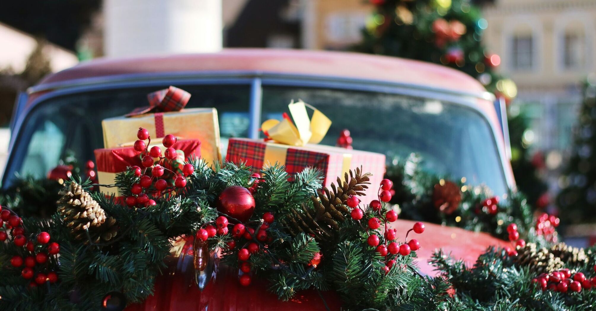 A festive car decorated with Christmas garlands and wrapped holiday gifts