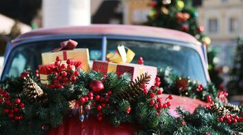 A festive car decorated with Christmas garlands and wrapped holiday gifts