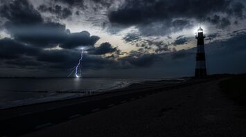 A lighthouse during a thunderstorm with lightning striking the sea