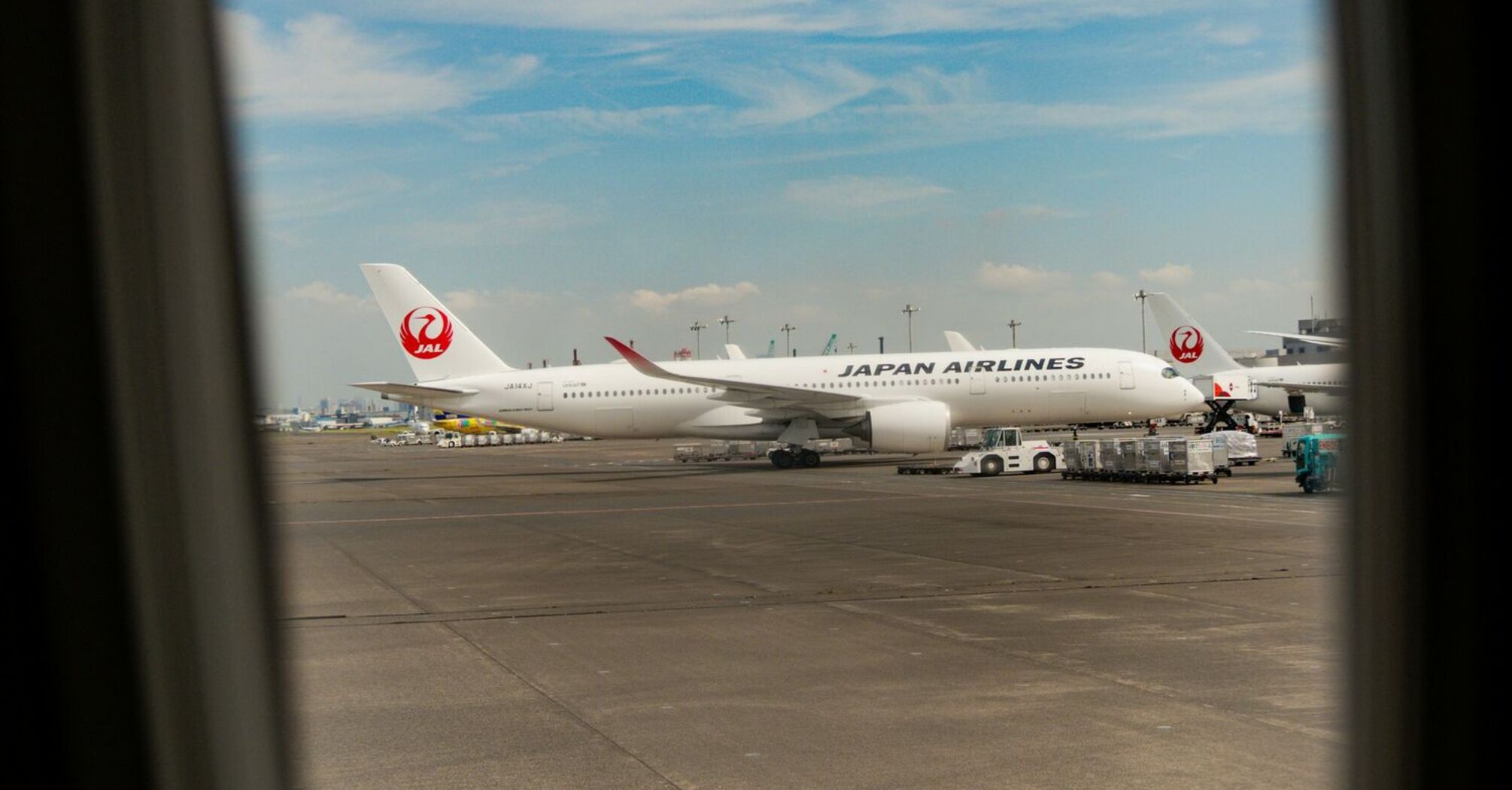 Japan Airlines aircraft on the tarmac viewed through an airplane window at Haneda Airport