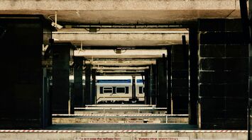 A Trenitalia train parked at an empty platform, surrounded by concrete pillars and caution tape
