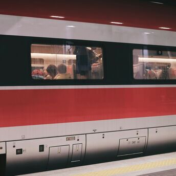 RFI high-speed train parked at a platform with seated passengers visible through windows