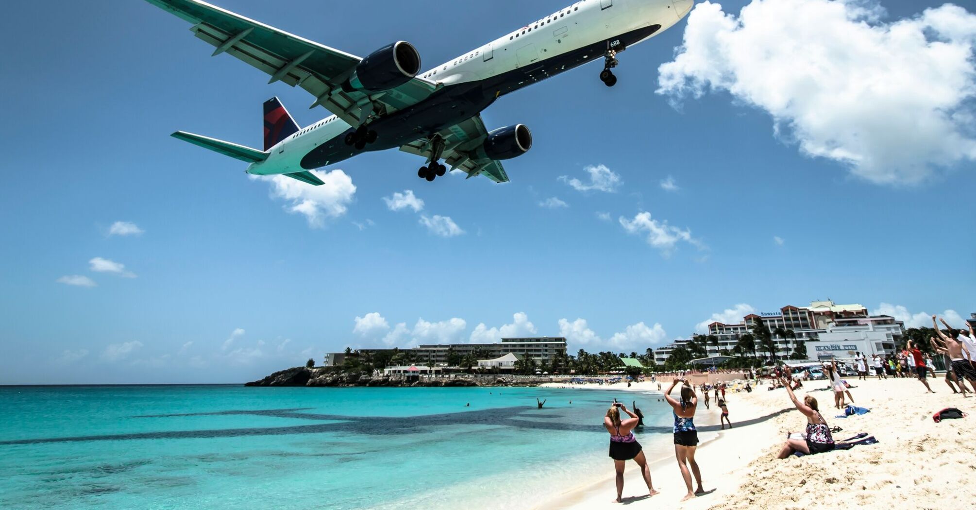 Delta airline plane landing over a tropical beach 