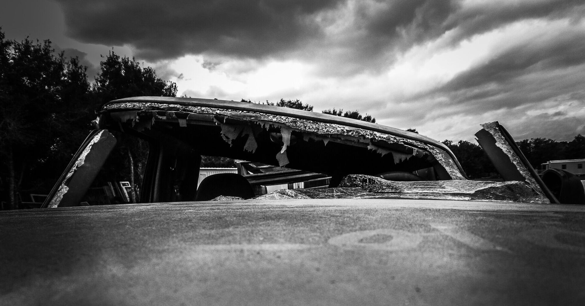 Car with shattered windows, under an overcast sky