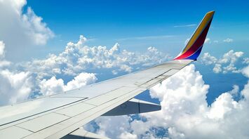 View of the wing of an airplane with a colorful tip Southwest Airlines, flying above the clouds under a blue sky 