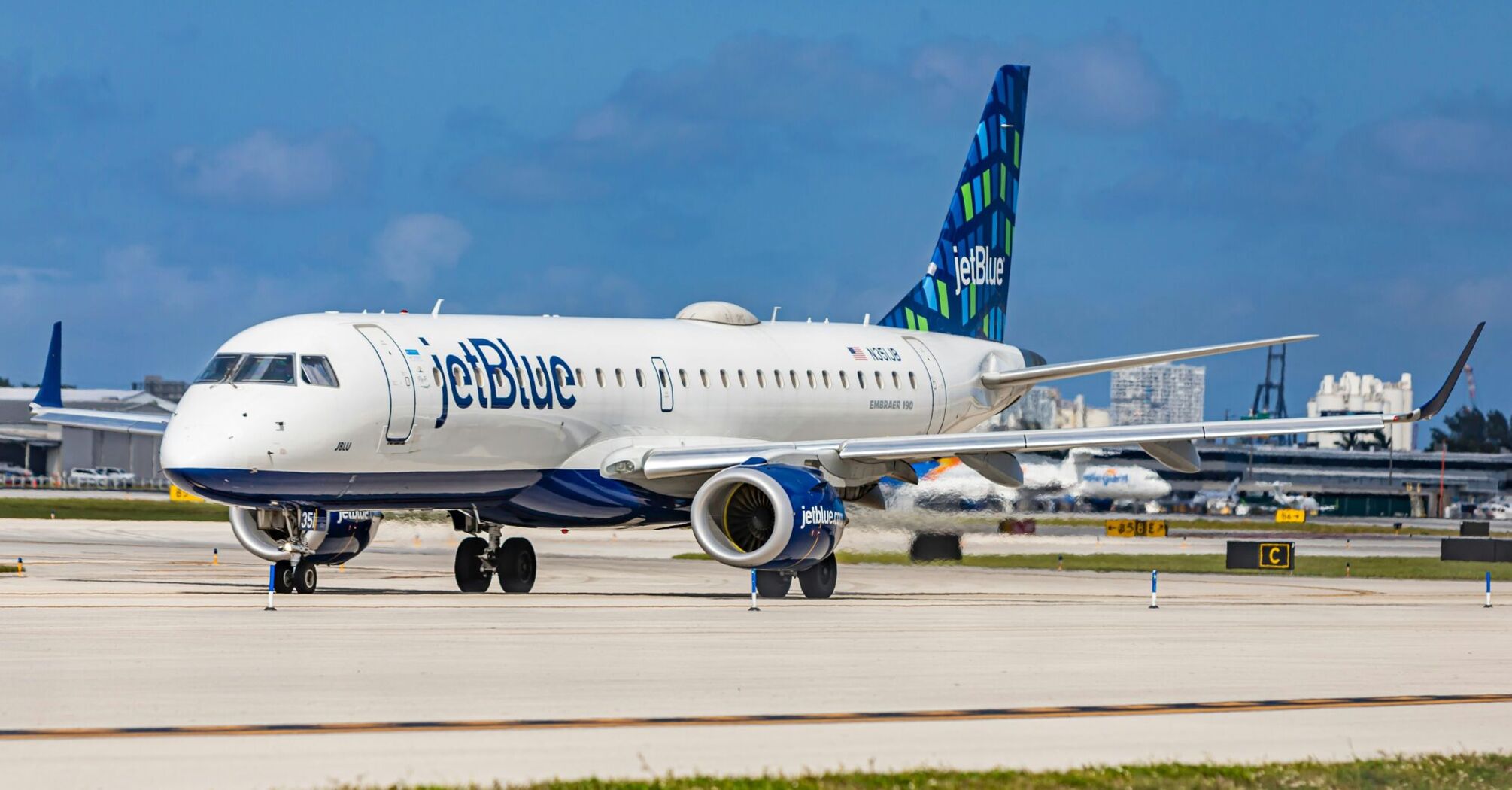 JetBlue Embraer 190 aircraft taxiing on the runway with the airline's distinctive livery