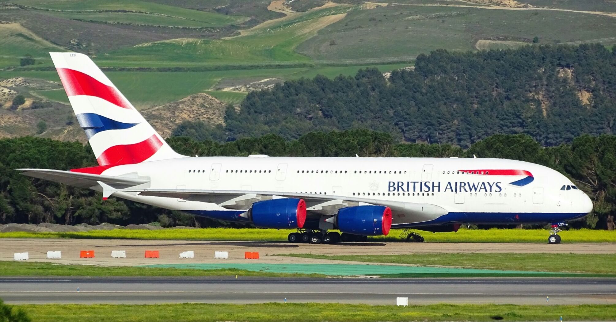 A British Airways aircraft on the runway with the company's signature red, white, and blue livery on the tail 