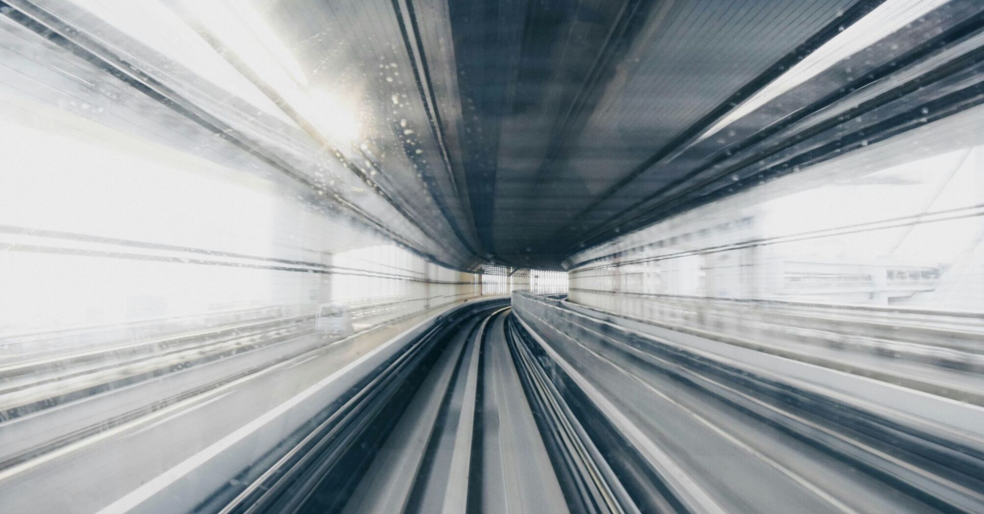 A motion-blurred photograph of a train's perspective traveling at high speed through a tunnel