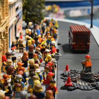 A vibrant LEGO scene depicting numerous LEGO minifigures bustling through a city street