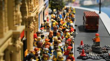 A vibrant LEGO scene depicting numerous LEGO minifigures bustling through a city street