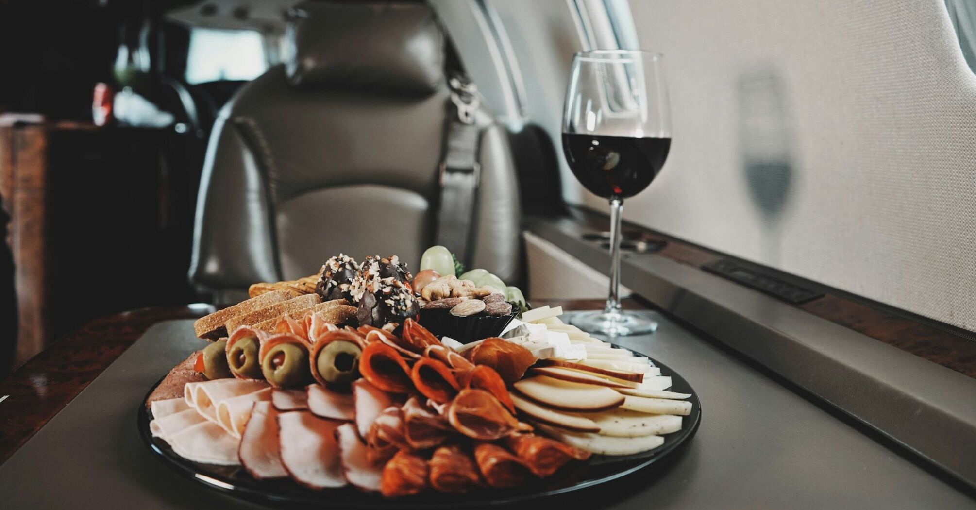 A gourmet charcuterie board with an assortment of meats, cheeses, and nuts, accompanied by a glass of red wine