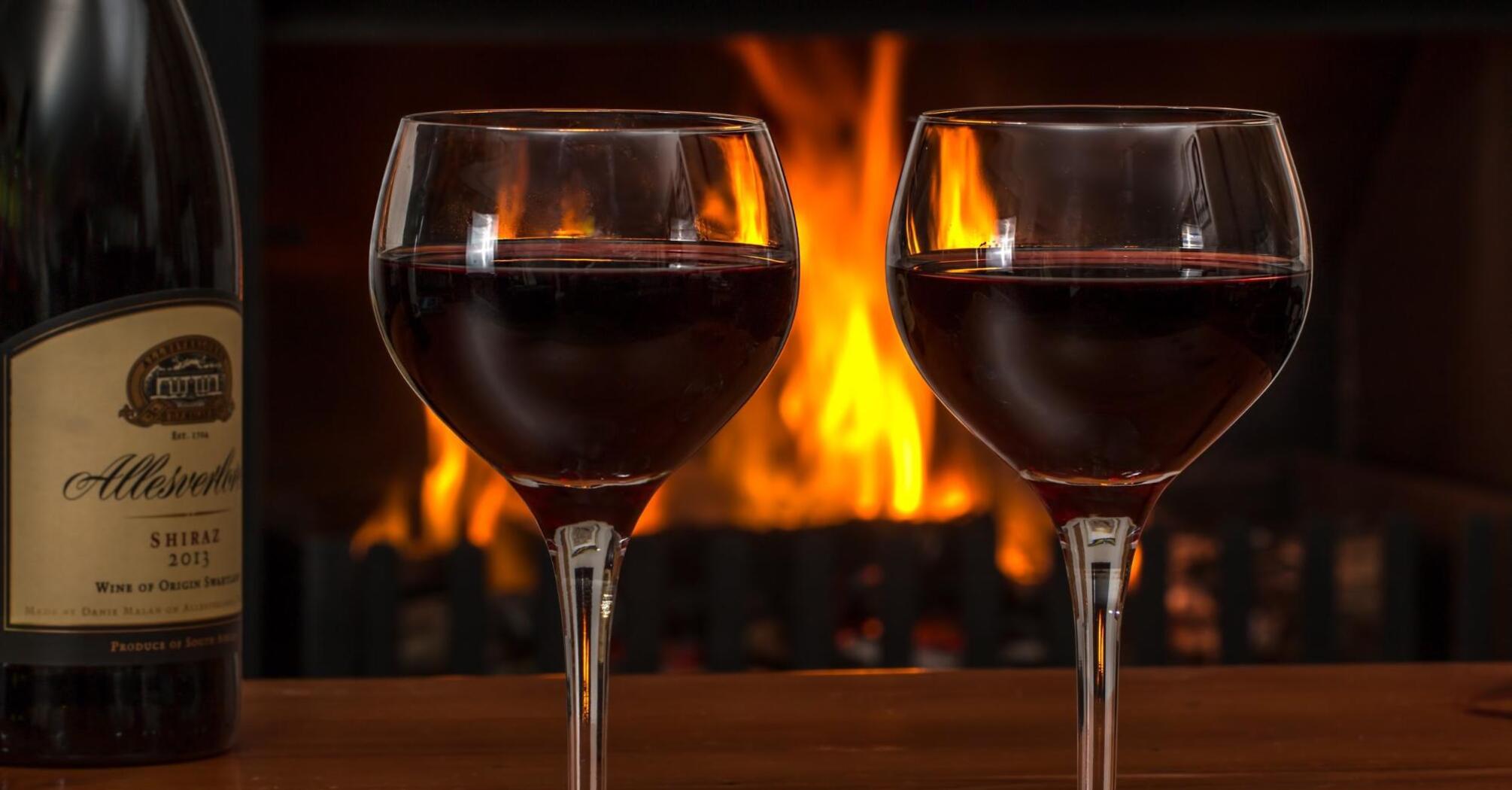 Two glasses of wine on the background of a burning fireplace