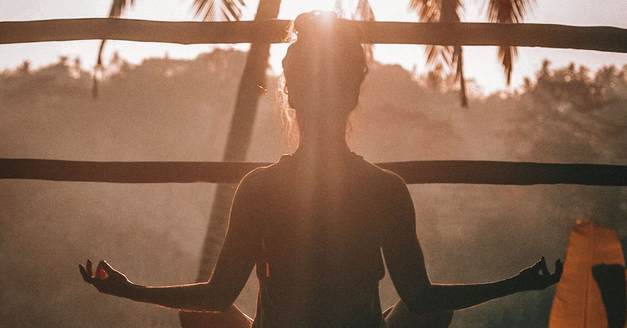 Silhouette of a person meditating with the sun setting behind them