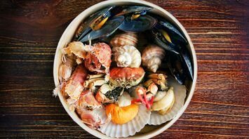 A variety of seafood including mussels, clams, and crab on a wooden surface