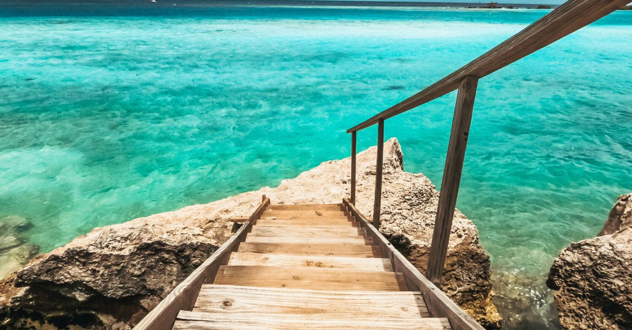 Wooden stairway leading down to clear turquoise waters in Aruba