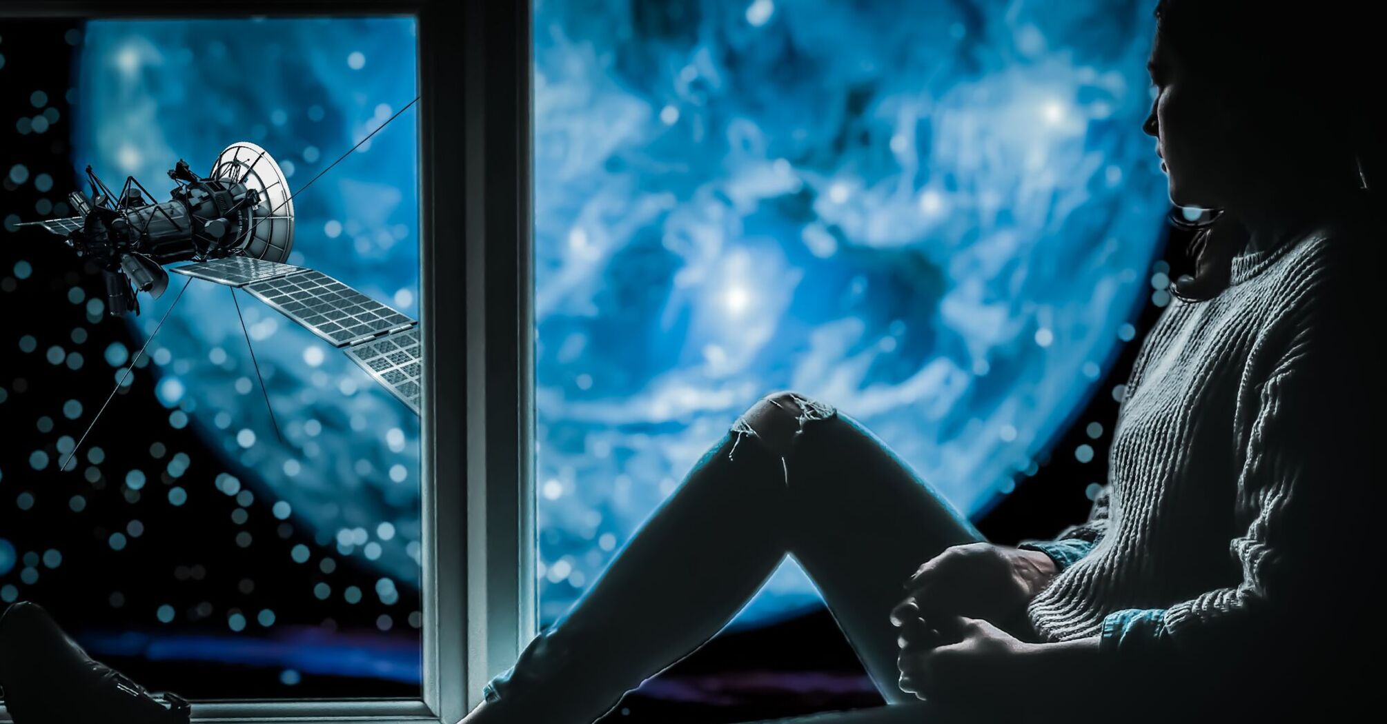 Silhouette of a person sitting by a window with a view of a satellite in orbit against a backdrop of Earth