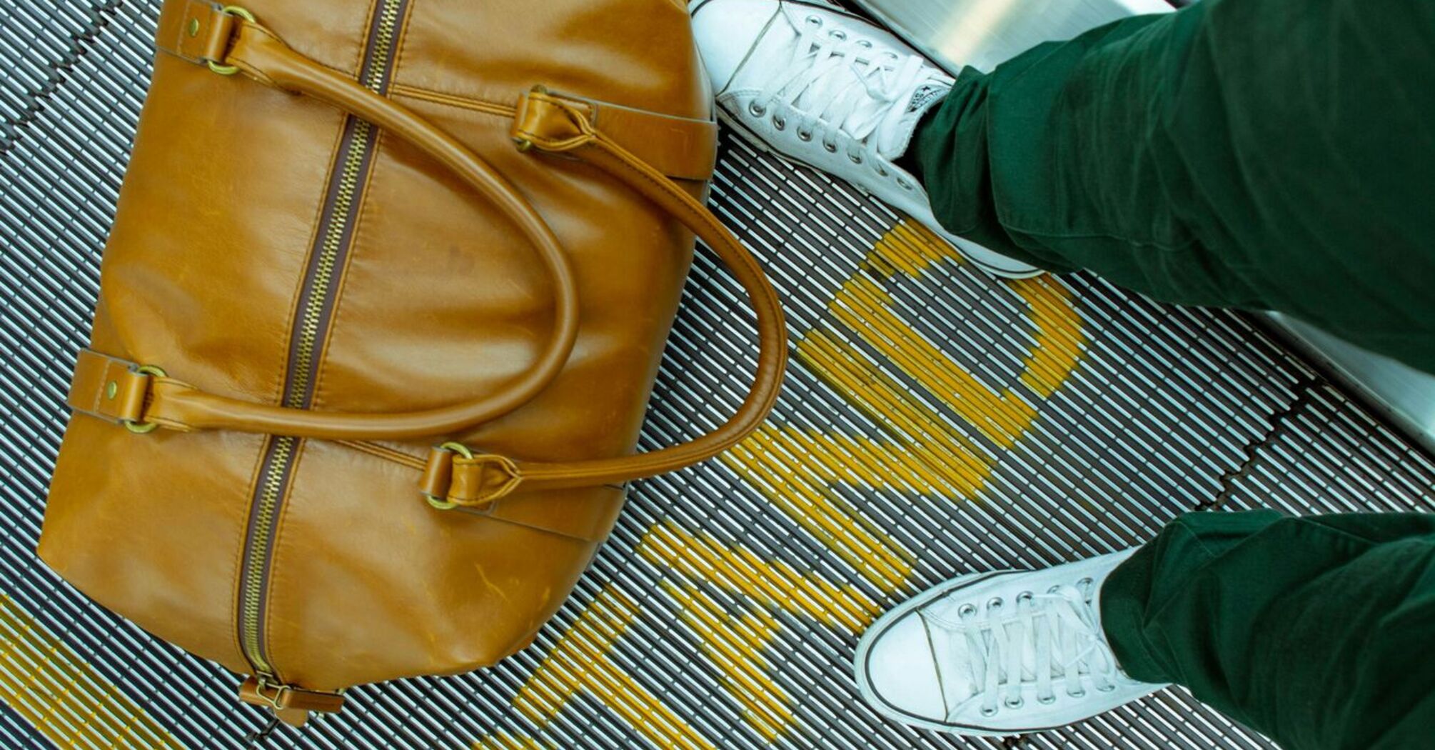 A traveler's tan leather bag on an airport conveyor belt