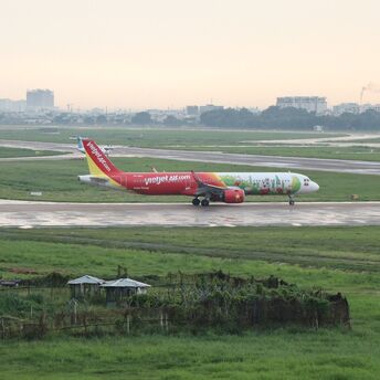  Vietjet Air airplane on the tarmac, with a view of the airport and green fields in the background