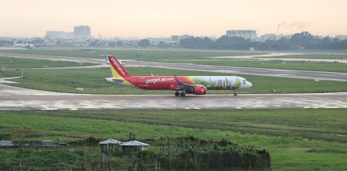  Vietjet Air airplane on the tarmac, with a view of the airport and green fields in the background