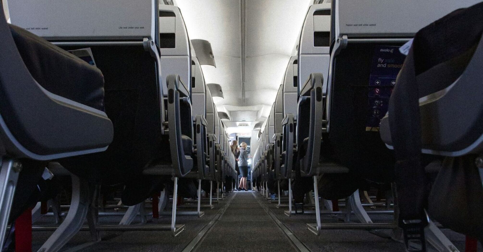 A view down the aisle of an airplane, showing rows of seats on either side