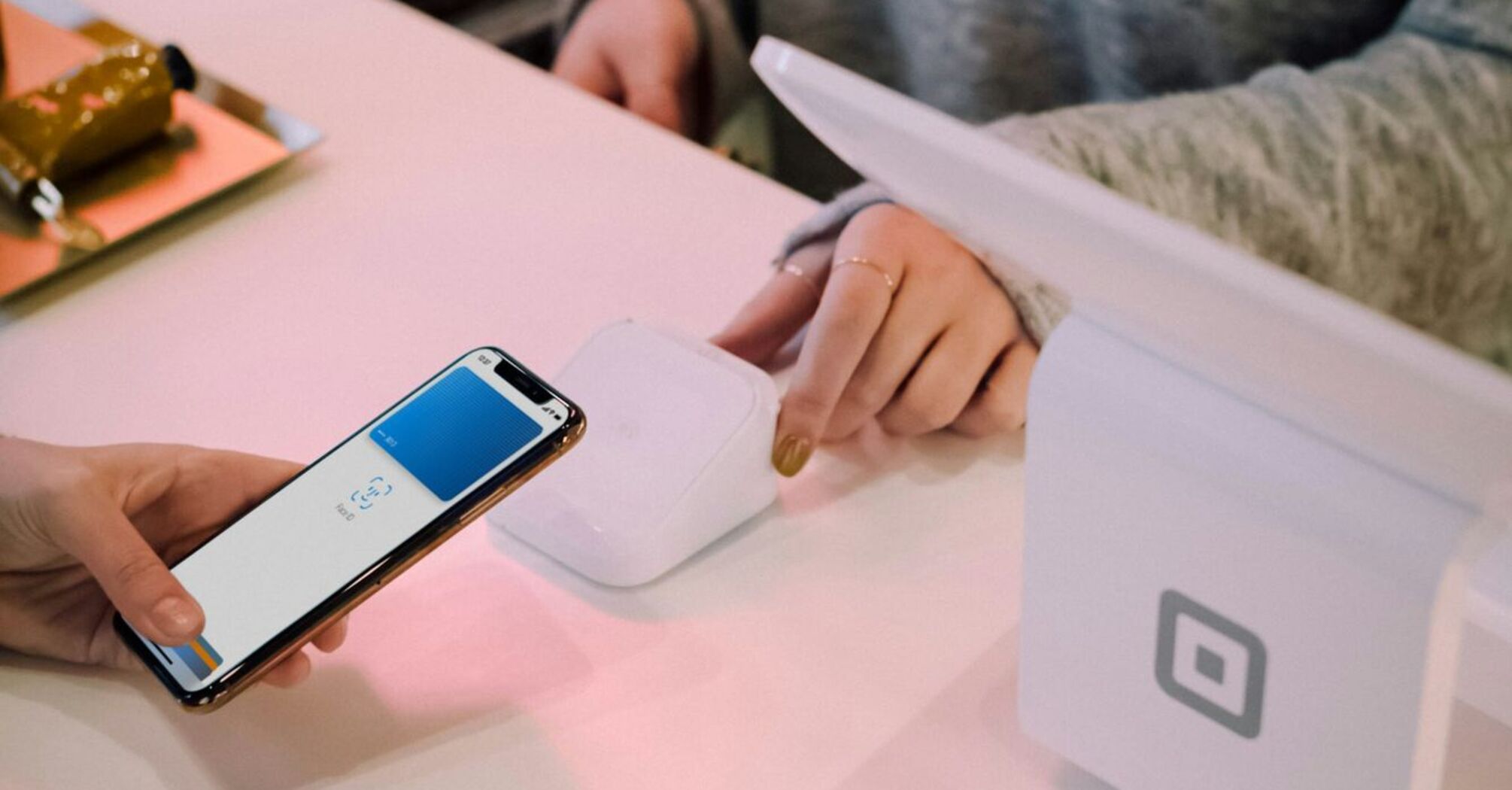 A customer is making a contactless payment using Apple Pay with their smartphone at a modern payment terminal