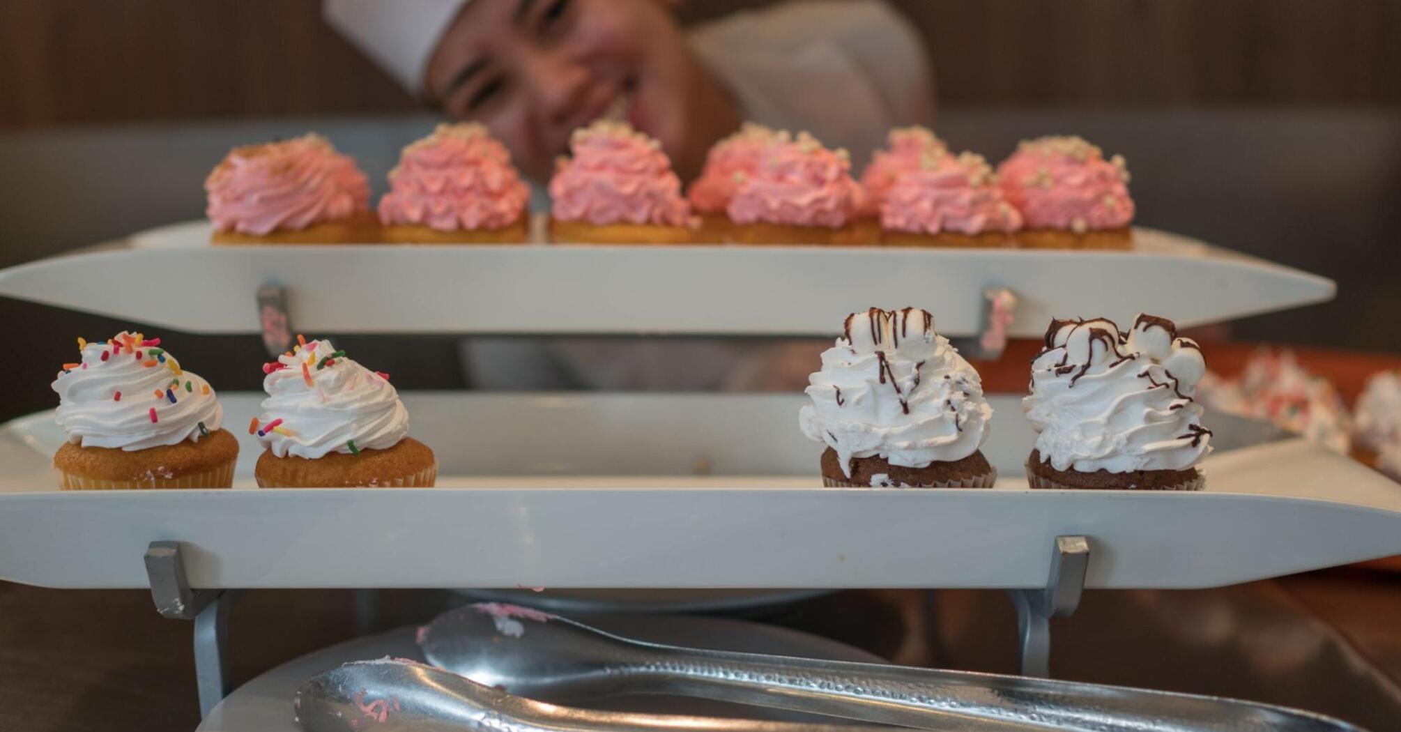 Female chef demonstrates her freshly prepared cupcakes