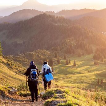 Hikers among the mountains lighted by bright sunlight 