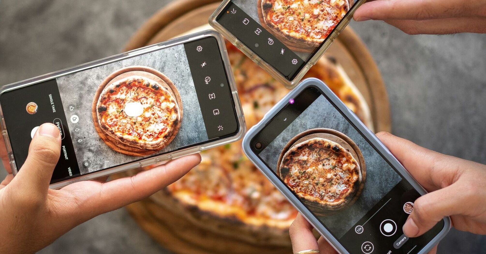Person holding black smartphone taking photo of pizza