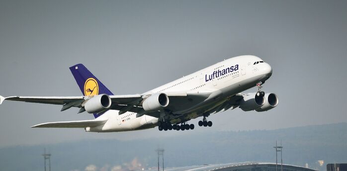 Lufthansa airplane taking off with airport in the background