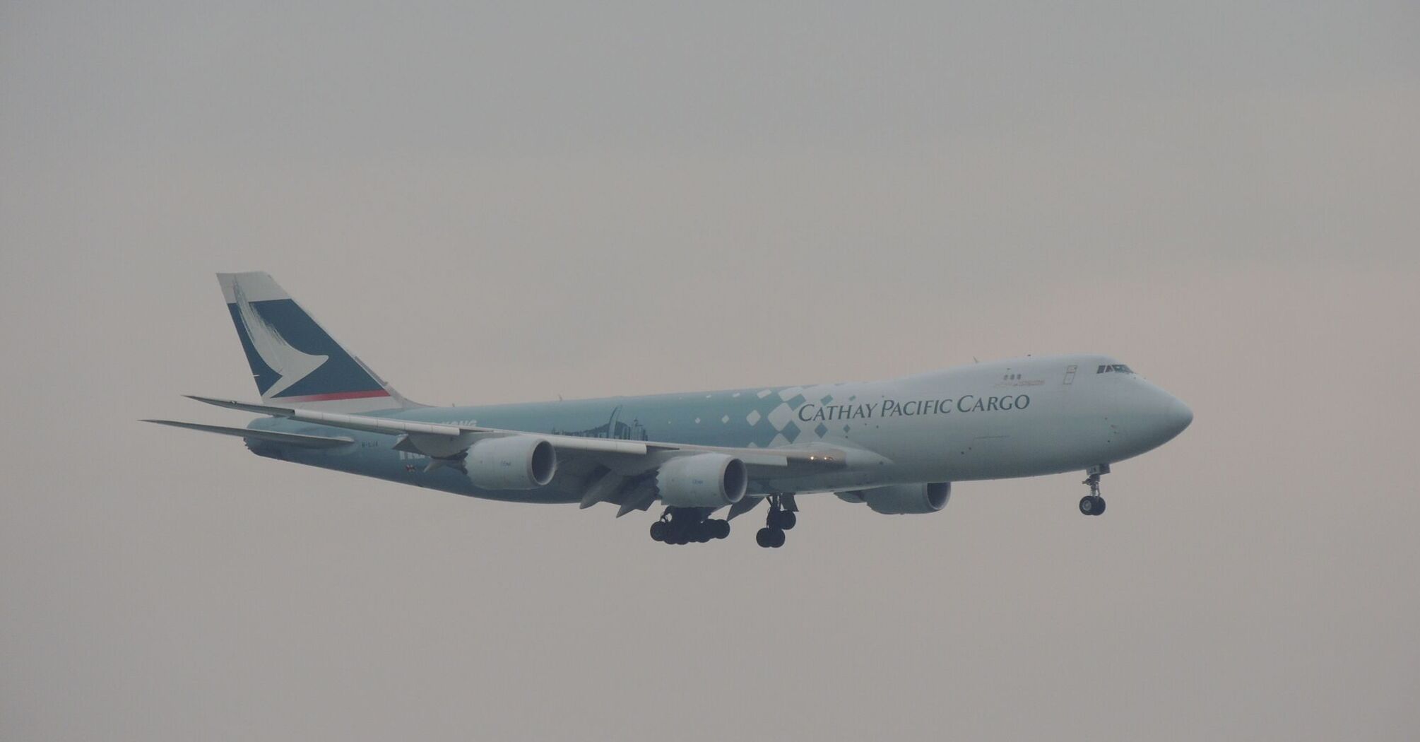 Cathay Pacific Cargo airplane in flight against a hazy sky