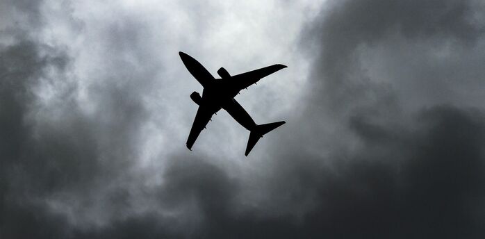 Silhouette of an airplane flying against a backdrop of stormy clouds