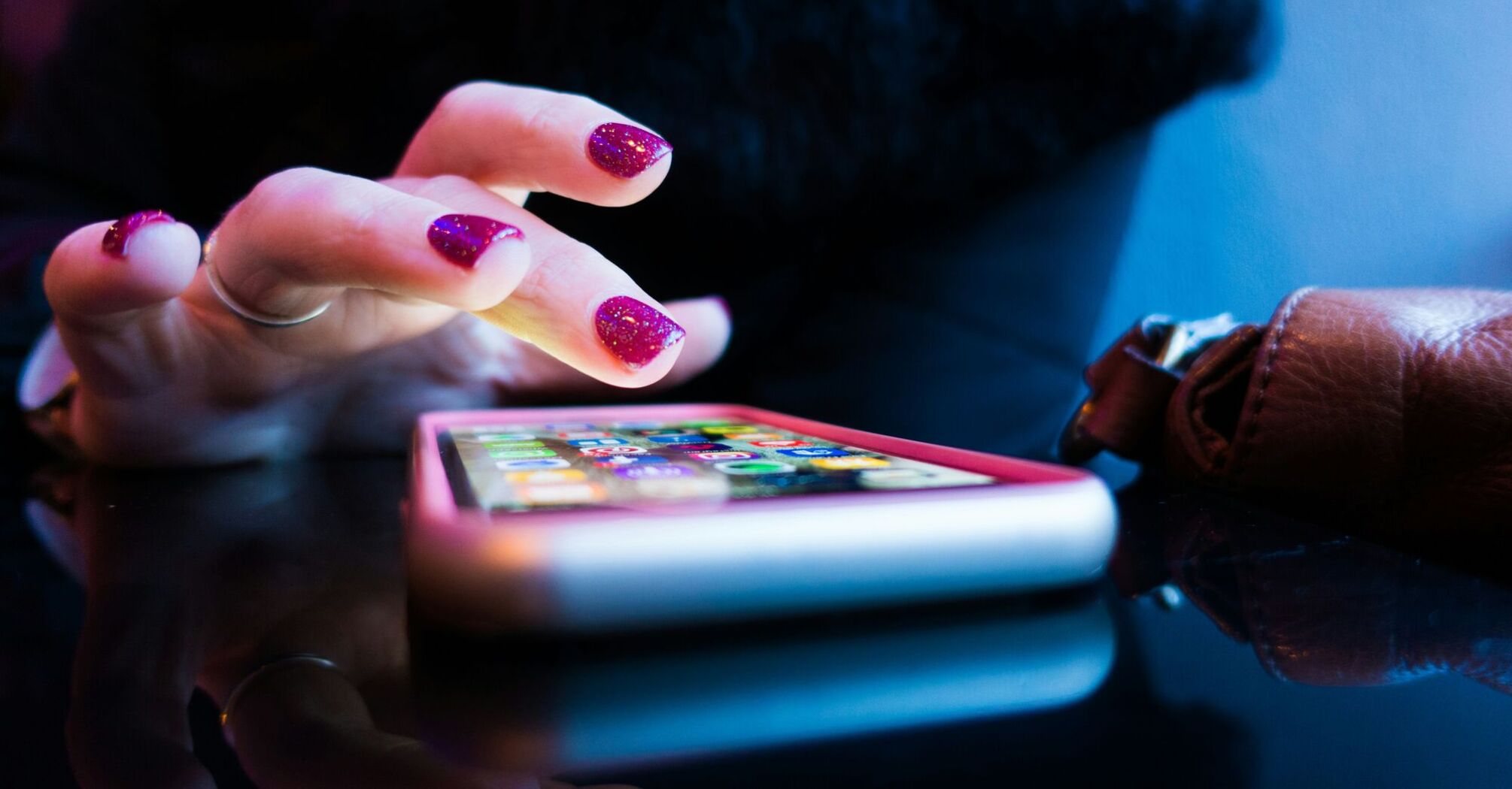 A person's hands using a smartphone, with the phone's screen showing colorful app icons 