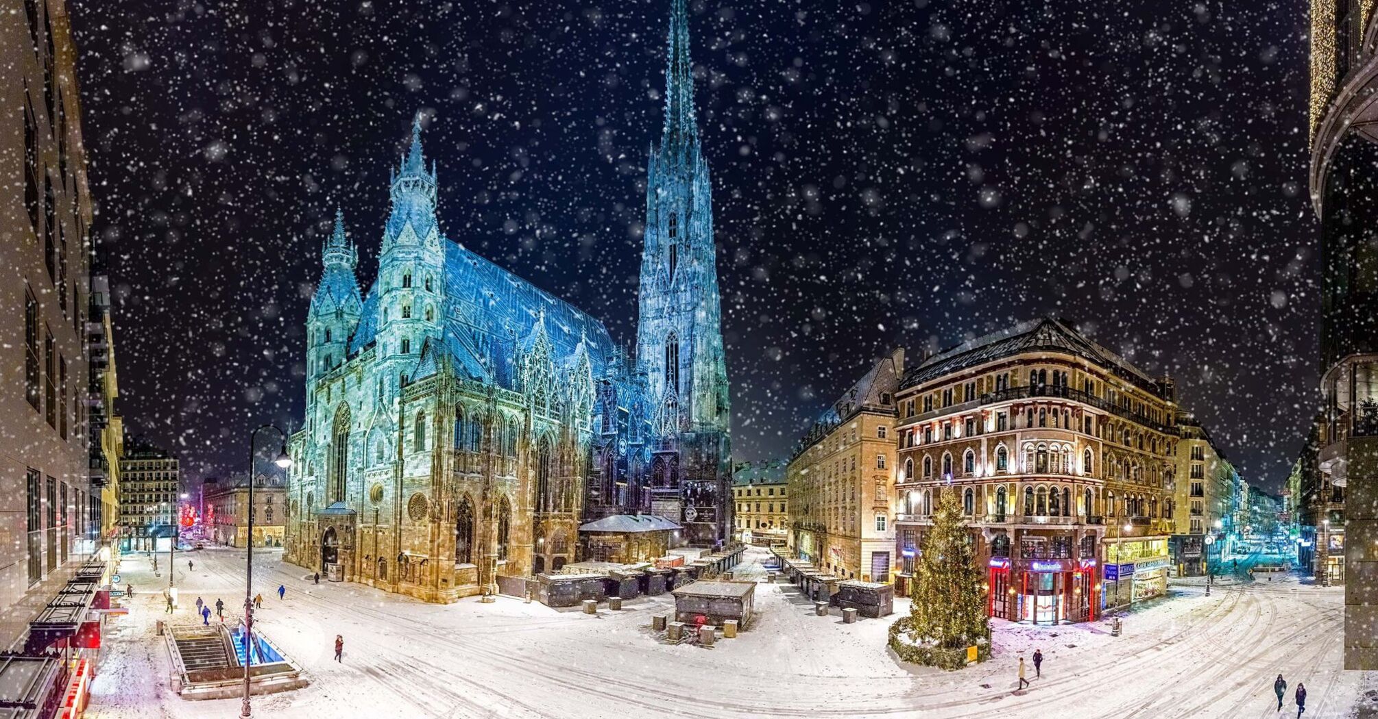 Snow-covered streets of Vienna at night with the illuminated St. Stephen's Cathedral and surrounding buildings