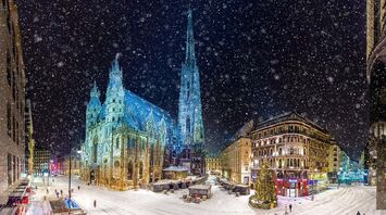 Snow-covered streets of Vienna at night with the illuminated St. Stephen's Cathedral and surrounding buildings