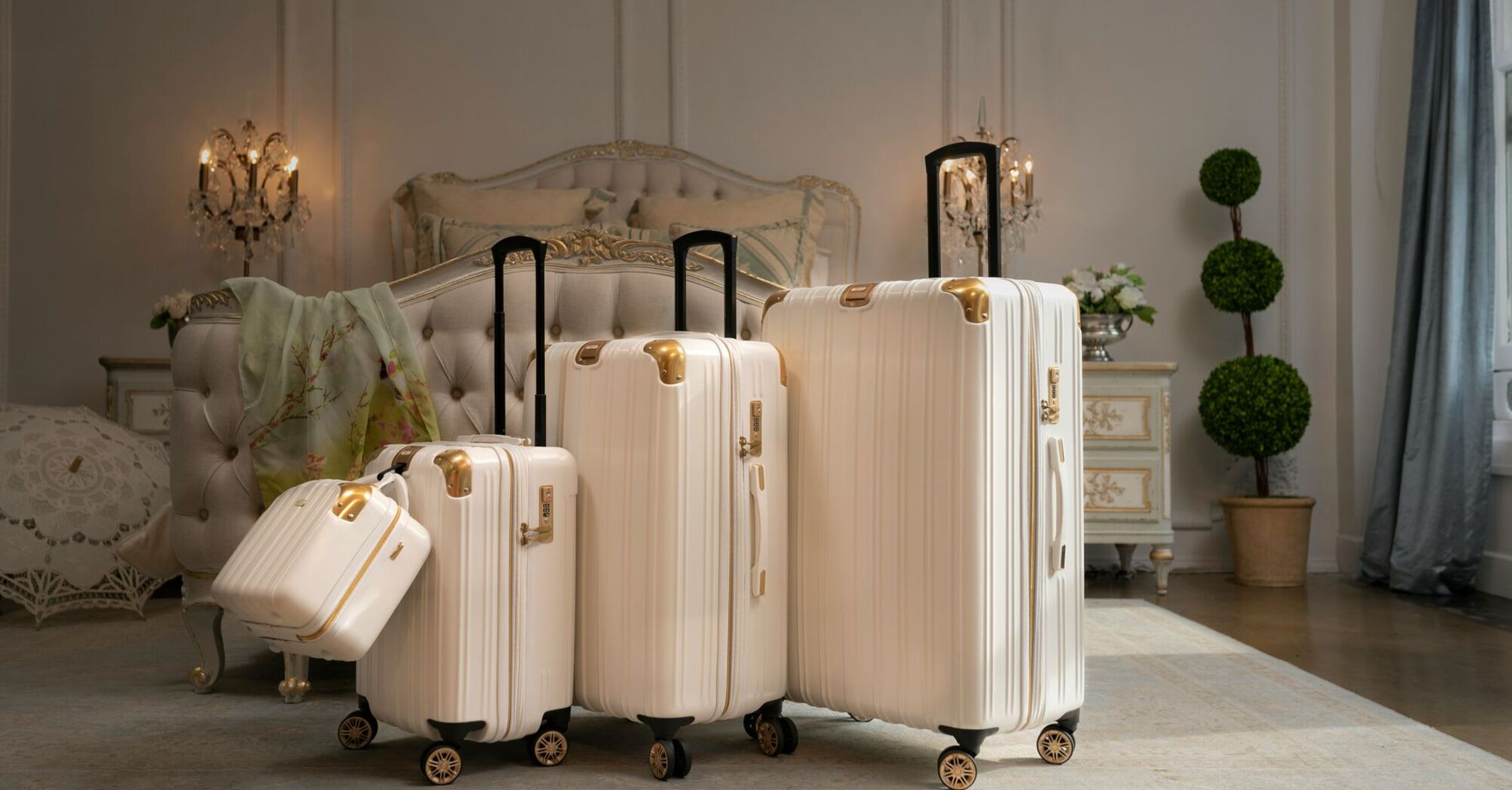 A set of elegant white luggage pieces of varying sizes, poised in a luxurious room with classic decor, ready for a travel adventure