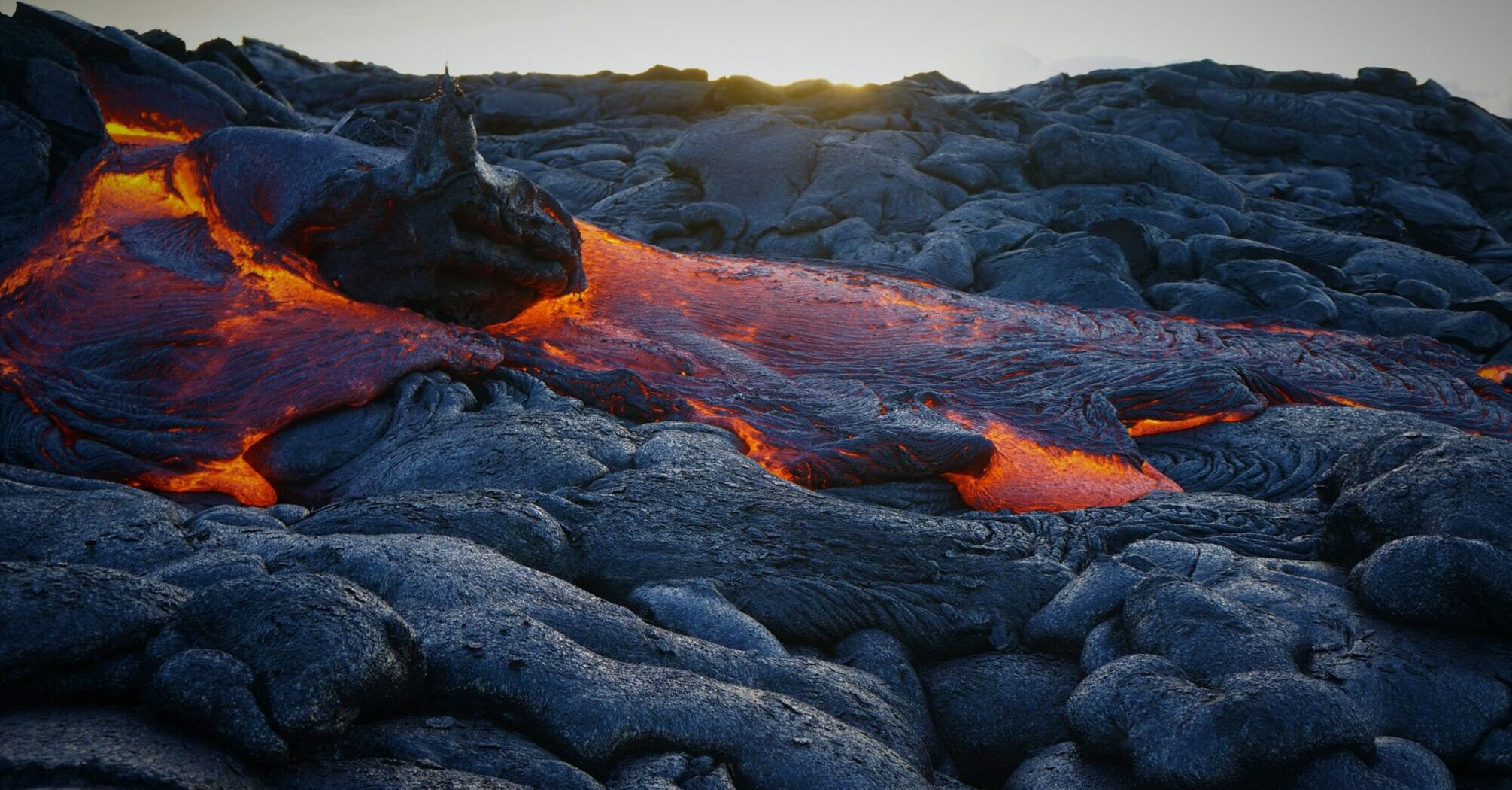 Flowing lava on the rugged terrain of Kīlauea at Hawaiʻi Volcanoes National Park 
