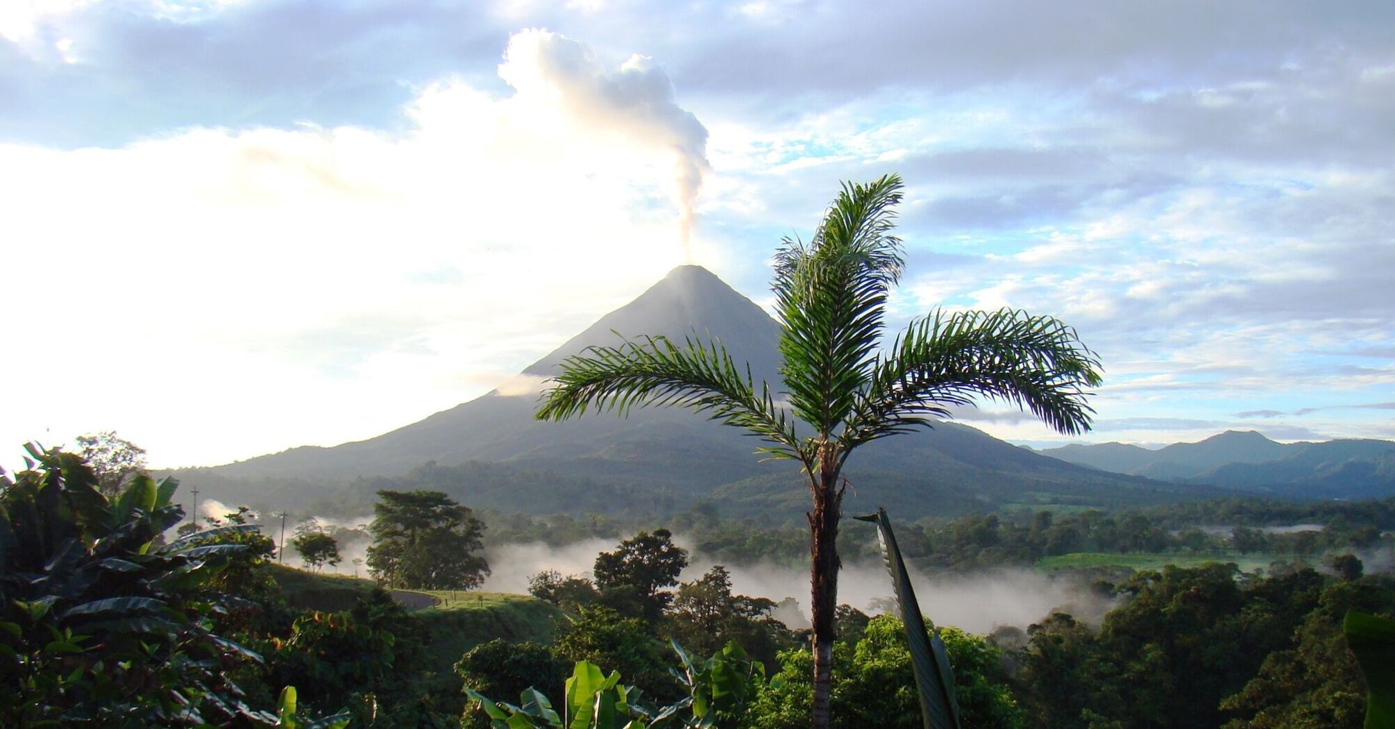 View of a volcano in Costa Rica, surrounded by tropical forest and low-lying clouds at sunrise