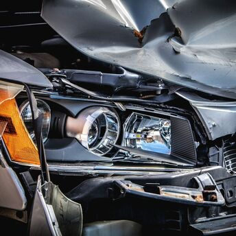 Severely damaged front end of a car with crumpled hood and broken headlight