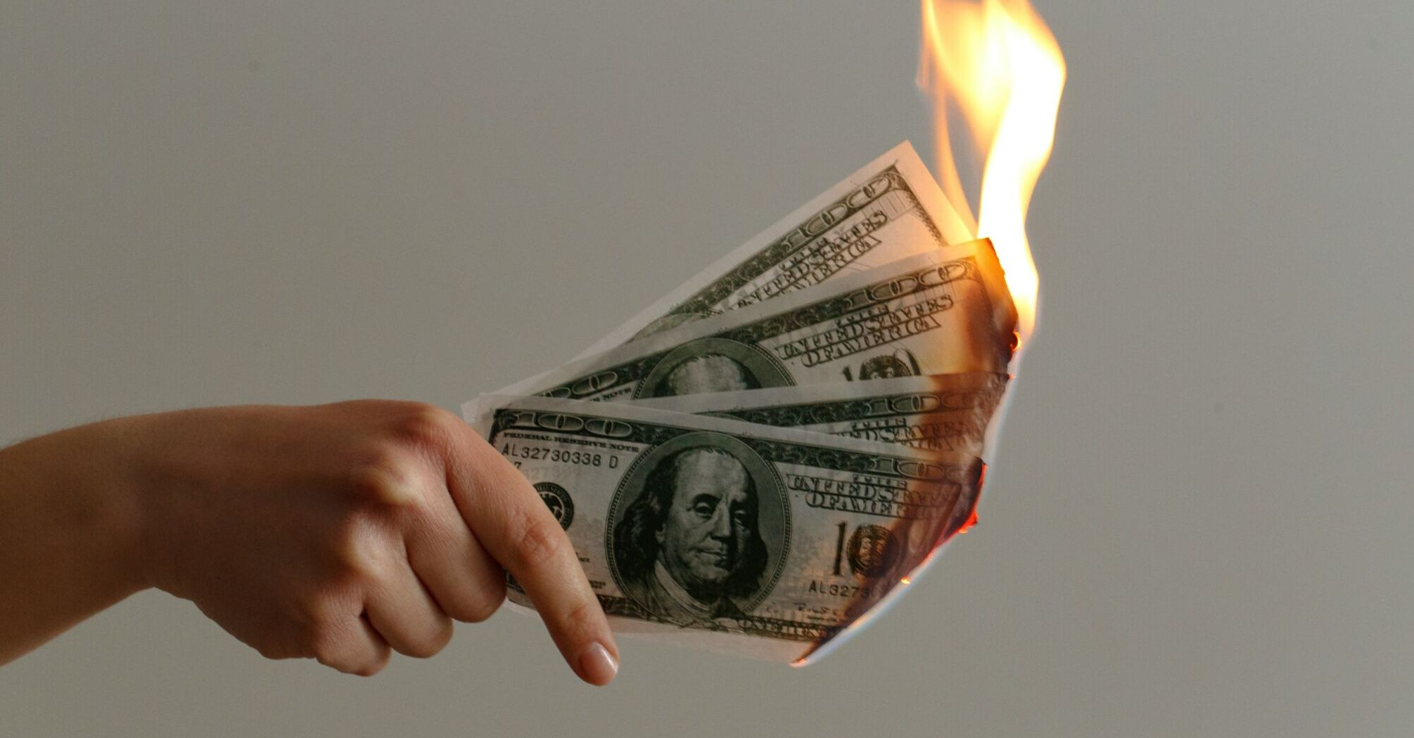 Person holding a bunch of dollar bills on fire