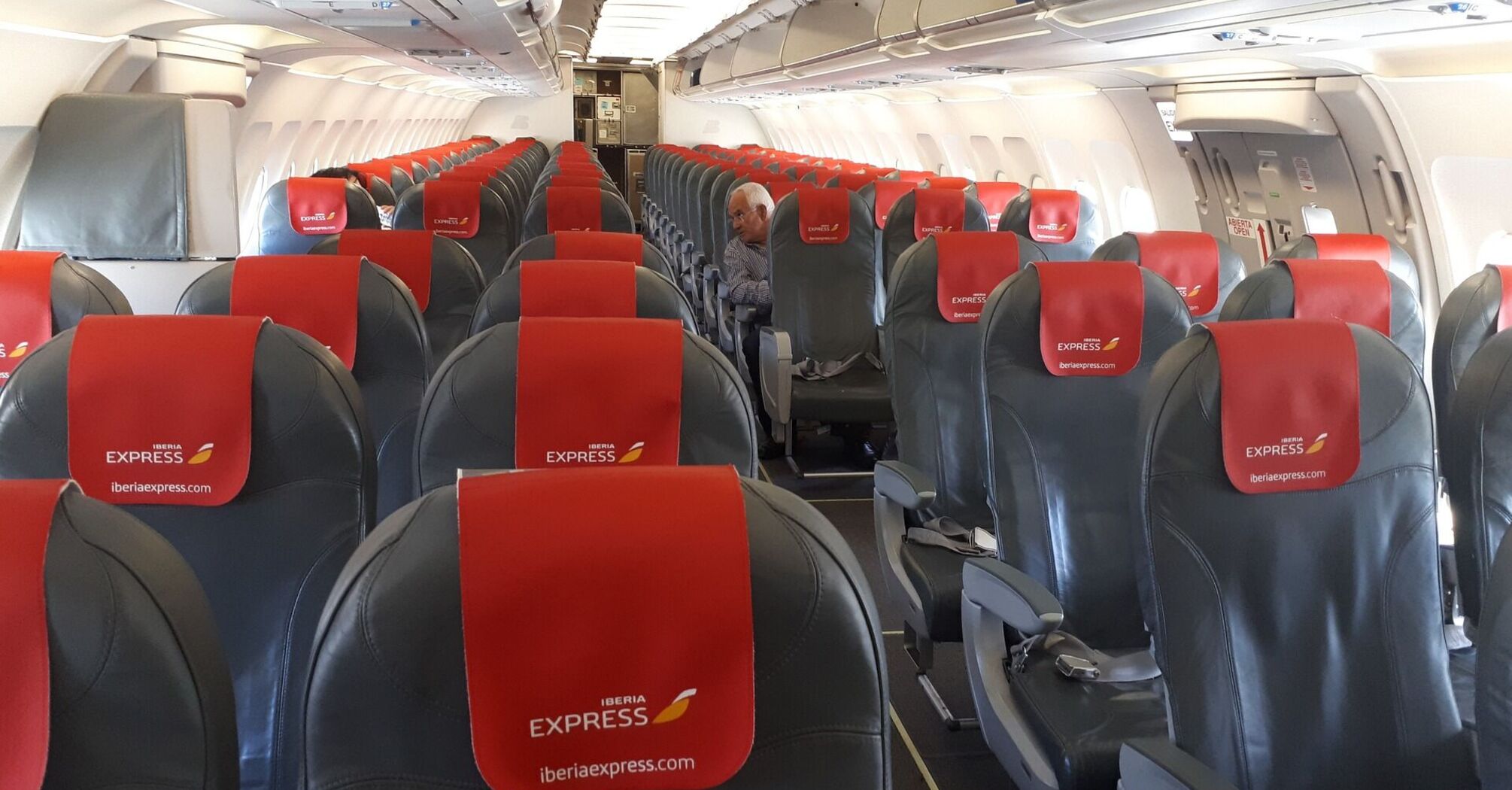 Interior of an Iberia Express aircraft showing rows of empty seats with red headrest covers featuring the airline's logo