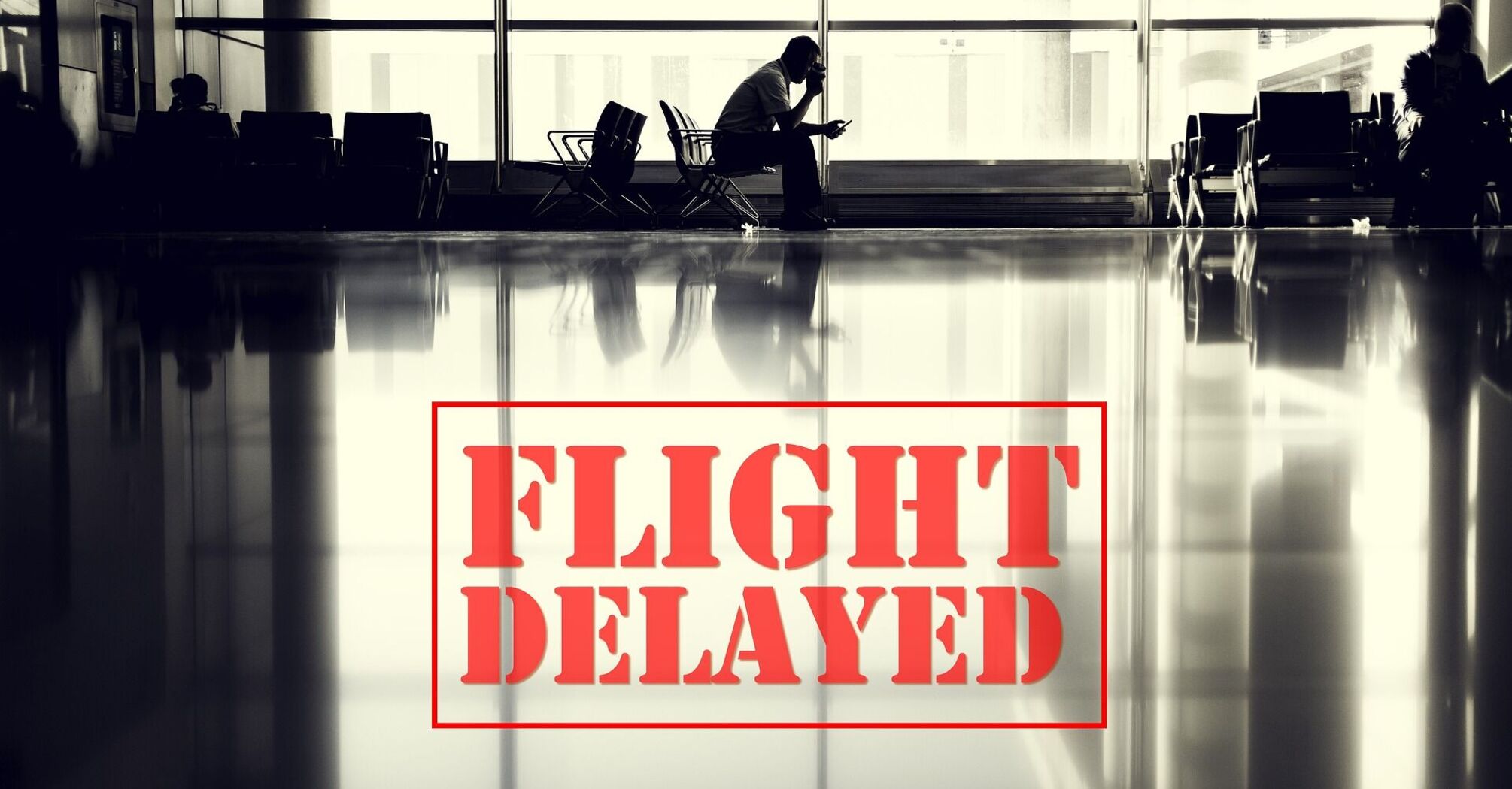 Silhouette of a person sitting in an airport terminal with the text 'FLIGHT DELAYED' overlaid