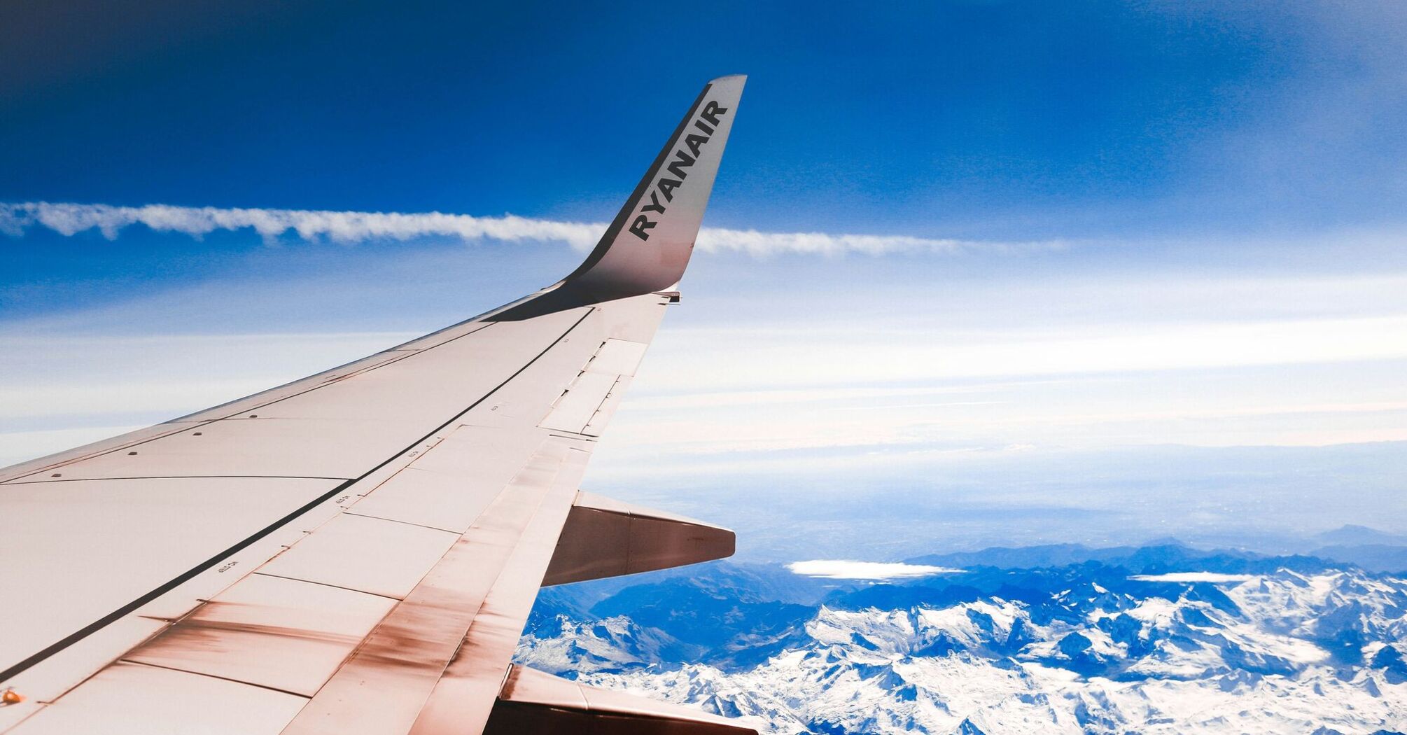 The wingtip of an Ryanair airplane against a clear blue sky