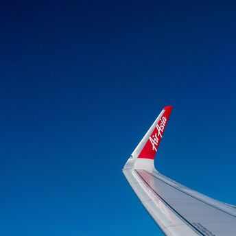 The wingtip of an AirAsia airplane against a clear blue sky