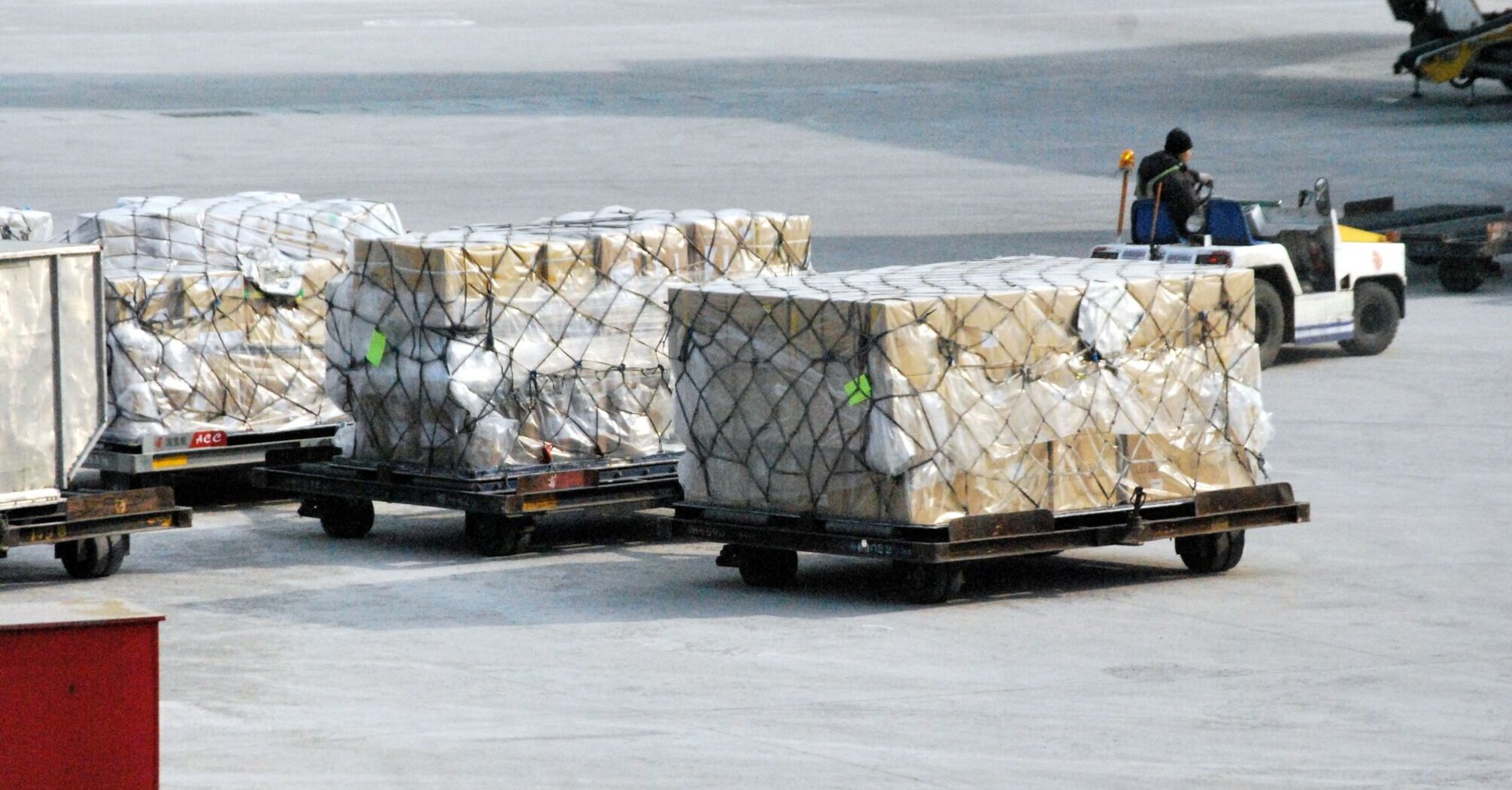 Air cargo pallets being transported on the tarmac by a cargo handler
