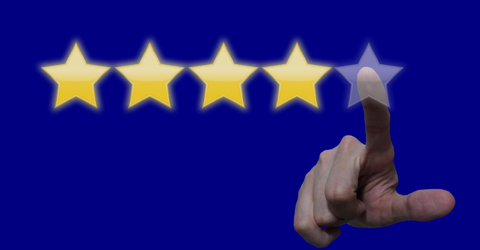 A hand reaching towards a row of five stars, with the fifth star being transparent, against a deep blue background